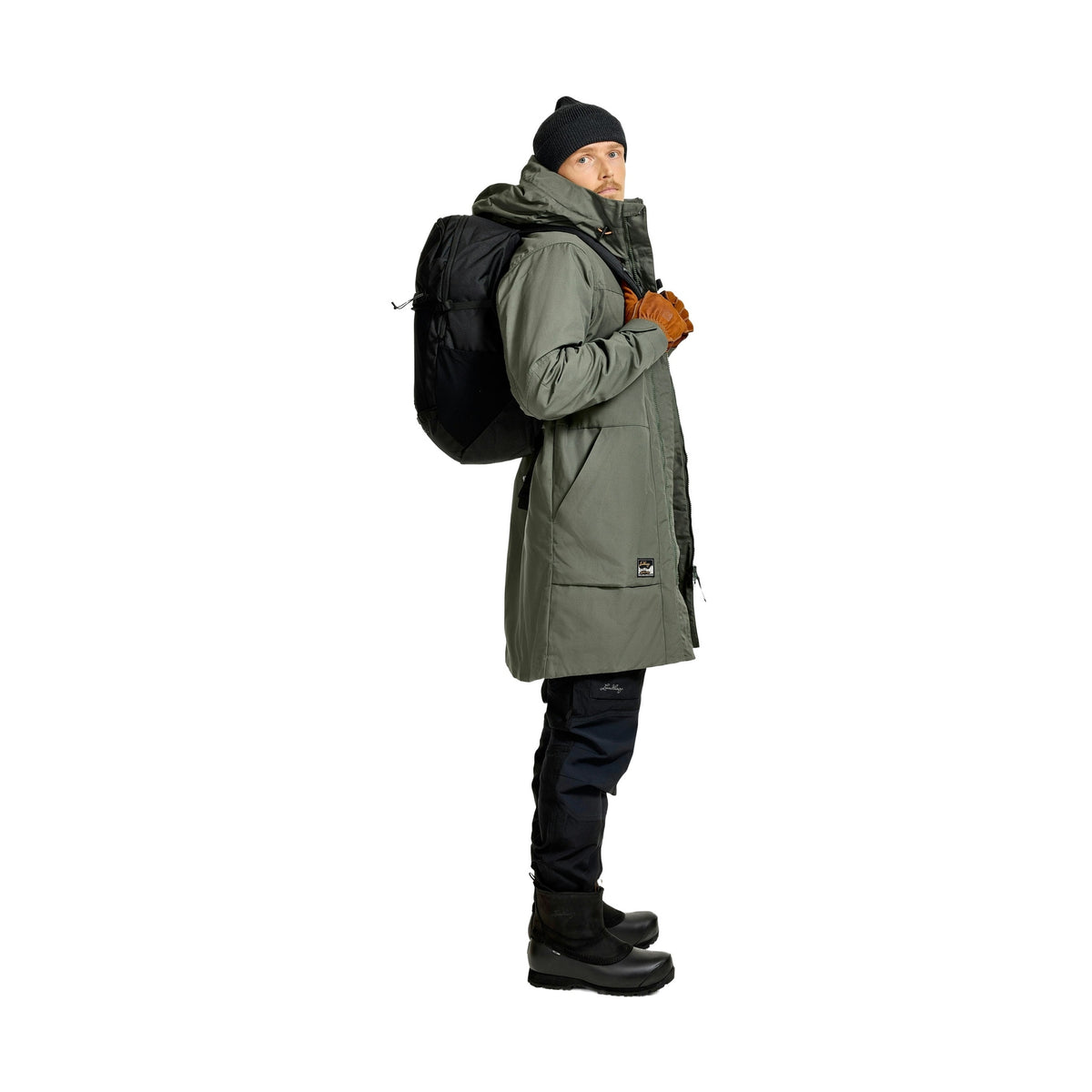 Sidovy av man i mörkgrön parka med ryggsäck