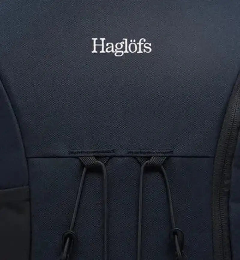 Mörkblå Haglöfs ryggsäck med vit logotyp och elastiska snören