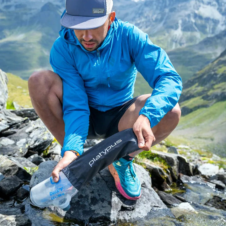 Man fyller Platypus QuickDraw-gravitationsfilter i bergsström