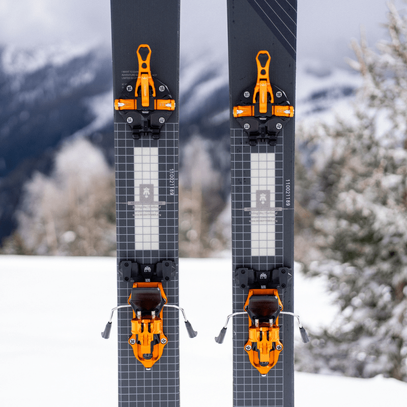 Orange ATK Freerider 15 EVO bindningar monterade på mörkgråa skidor i snö