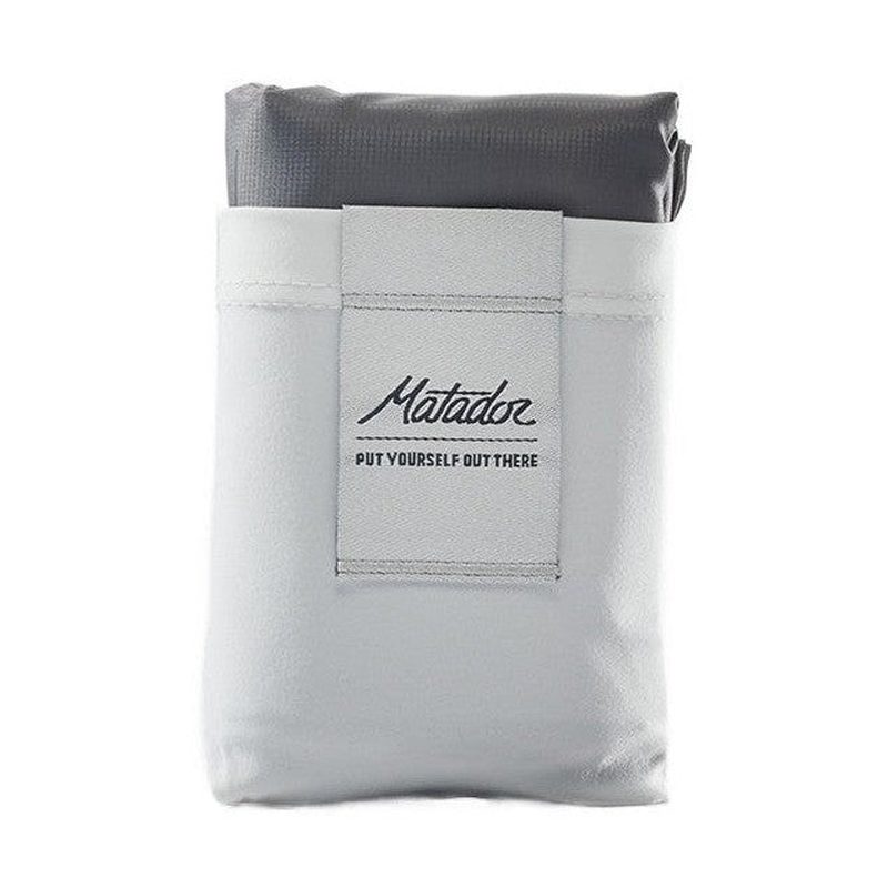 Packad Matador Pocket Blanket i grått med vävt fodral och svart logotyp