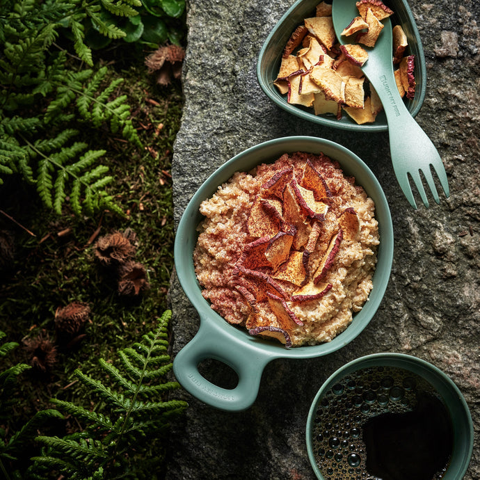 Grön kåsa med havregröt och spork i skogen