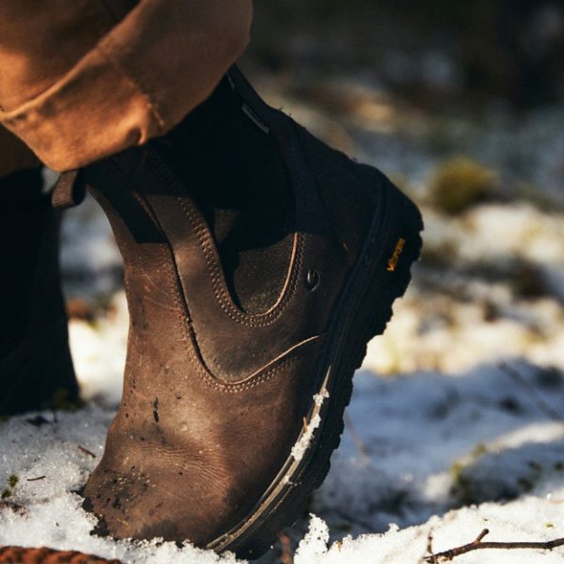 Närbild på mörkbrun läderchelseabo med Vibram-sula i snö