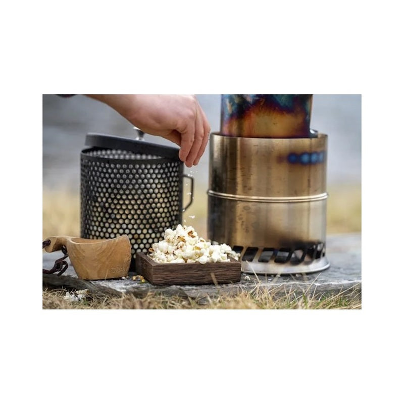 Popkornsgryta vid brännare med färdig popcorn och lock