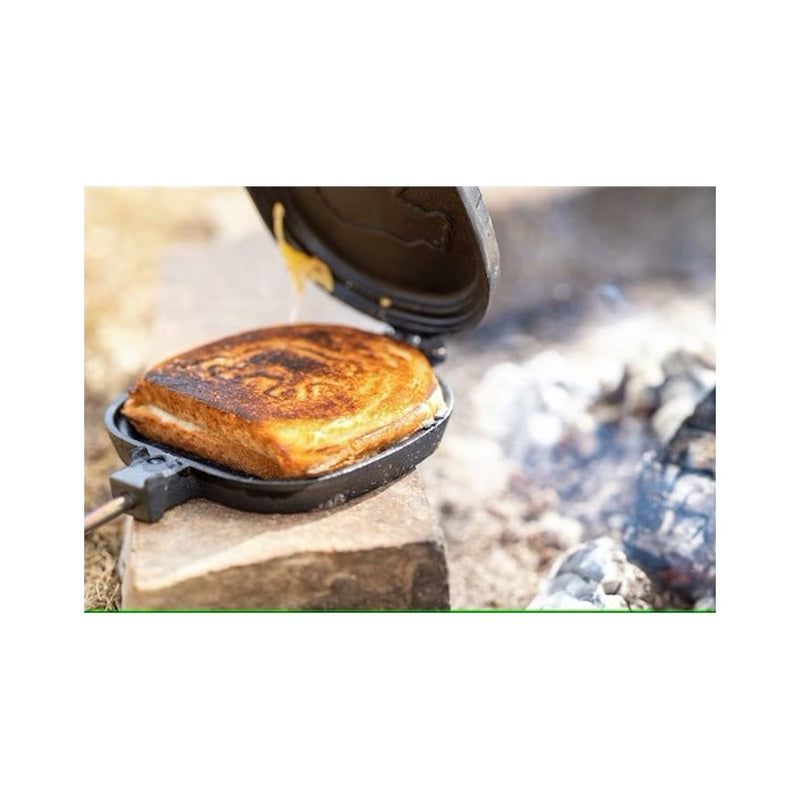 Gjutjärnsgrill med älgmotiv grillar smörgås över bål